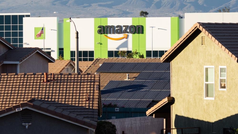 Photo of a large Amazon warehouse with residential houses in the foreground